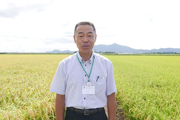 「新之助」のブランド化を進める新潟県農林水産部農業総務課政策室の神部淳室長。神部氏の後ろには「コシヒカリ」(左)と「新之助」(右)が実っている
