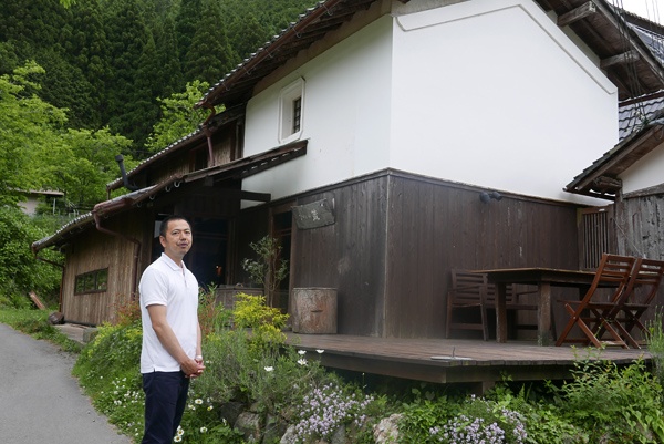 シェフとして切り盛りするフランス料理店「ひわの蔵」を前に、丸山集落のことを「集落という名の家族だ」と語る村木伸也さん。1973年生まれ。1年前にIターンで集落の住人となった。この店のすぐ前にある畑で野菜を作り始め、「いずれここで収穫したもので料理を作りたい」と考えている(写真:高山和良)