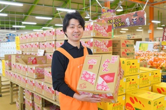 冬の果物の主役、みかんの箱を手にする岡田芳和店長(写真=水野浩志)