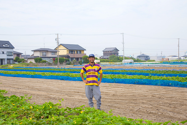 営農する畑で笑顔を見せる鈴木淳基さん。８月から３月までは玉ねぎづくりに全力を傾ける。その裏作として現在は冬瓜とさつまいもの生産をしている（写真：佐藤久）
