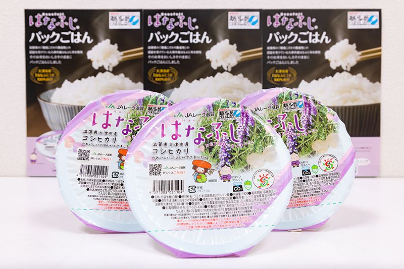 「はなふじ」パックごはん。滋賀県「環境こだわり農産物」の認証を受けた、滋賀県産コシヒカリ。ヘアリーベッチという一年草を栄養源とするため、肥料不要で育つ。ヘアリーベッチが温室効果ガスをオフセットすることから、全国で初めて米のカーボンオフセット製品として認証された