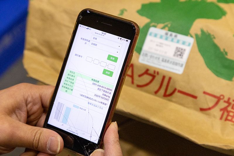 実際に貼付されたQRコードと、スマートフォンで読み取る様子