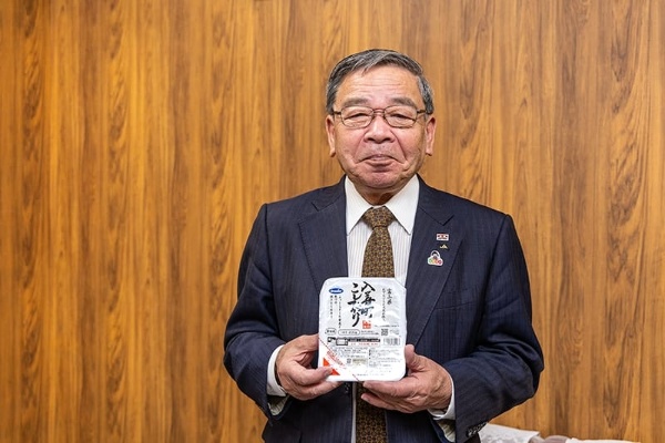 取材終了後、ウーケのパックご飯を両手に笑顔で撮影に応じる細田氏