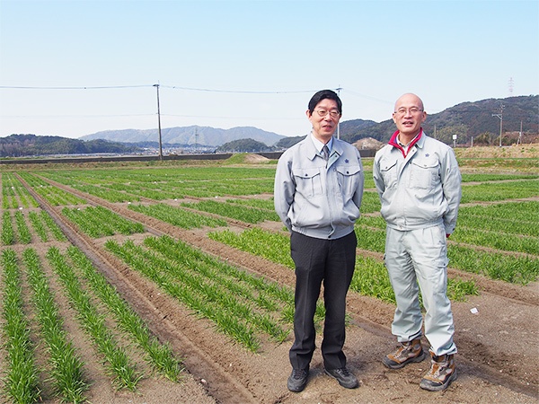 遠くに宝満山を望む圃場で並ぶ田中さんと甲斐さん