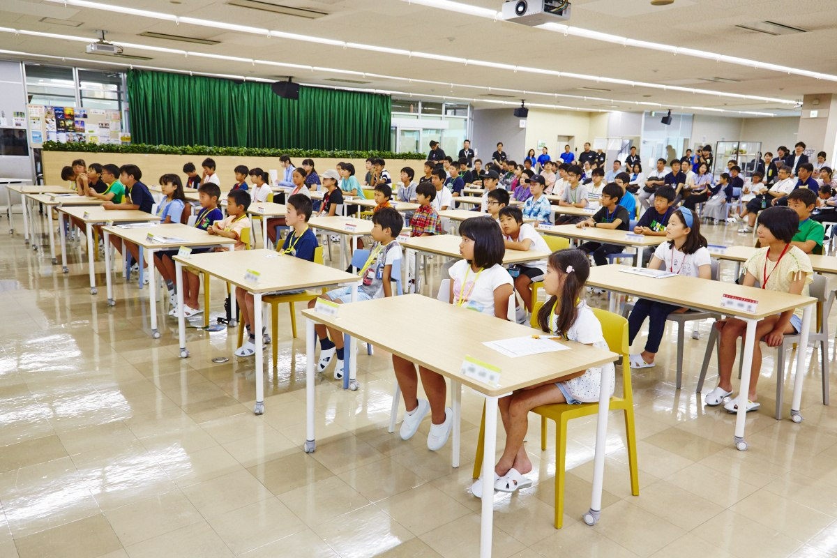 普段は食堂として使われている場所だが、開校式や閉校式の会場として使用された。前方の大型スクリーンに向かって50名の生徒たちがテーブル席に付き、後方にはその父親や母親など同伴者が着席している。