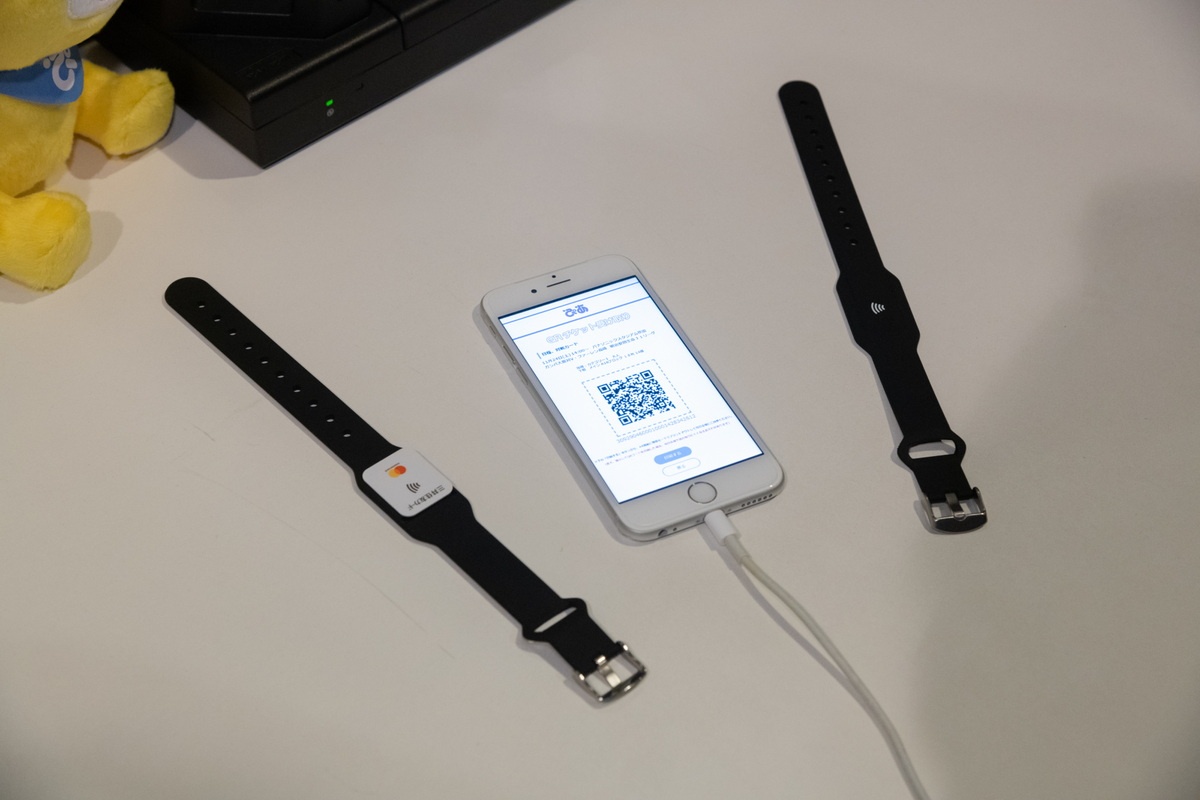 実証実験ではリストバンド型の非接触型ウェアラブルICを入れた電子チケットを配布する。